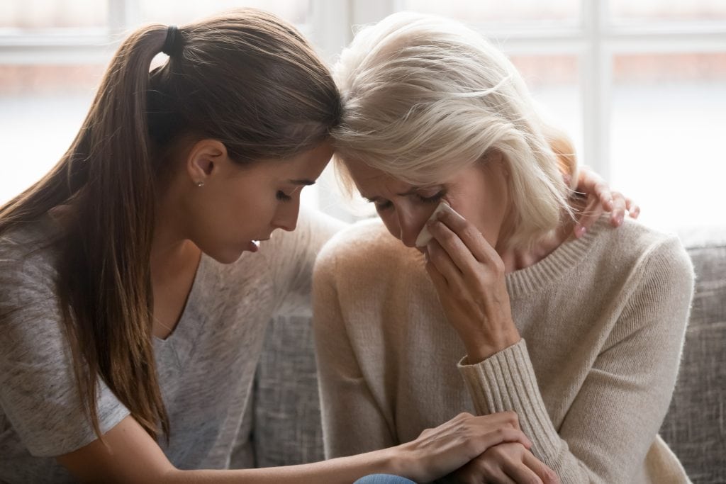 Picture of an elderly woman grieving, being consoled by a young woman