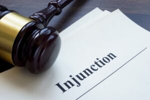 An image conveying the subject of injunctions, the image being A document with the word Injunction, and a gavel