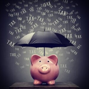 An umbrella shelters a piggy bank from large number of the word TAX, falling like raindrops. A visual image corresponding to the Credit Shelter Strategy.